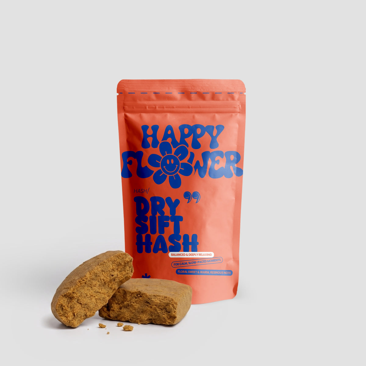 Happy Flower Dry Sift Hash in korallfarbener Standbeutel-Verpackung mit zwei goldbraunen Hasch-Stücken und kleinen Krümeln auf hellem Hintergrund.