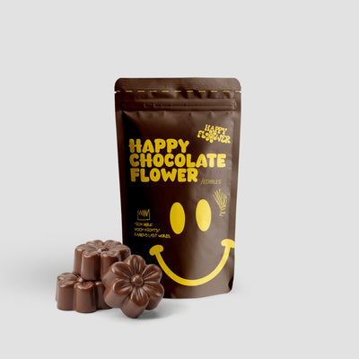 Happy Flower Happy Chocolate Flower Edibles in brauner Standbeutel-Verpackung mit mehreren blütenförmigen Schokoladenstücken im Vordergrund auf hellem Hintergrund.